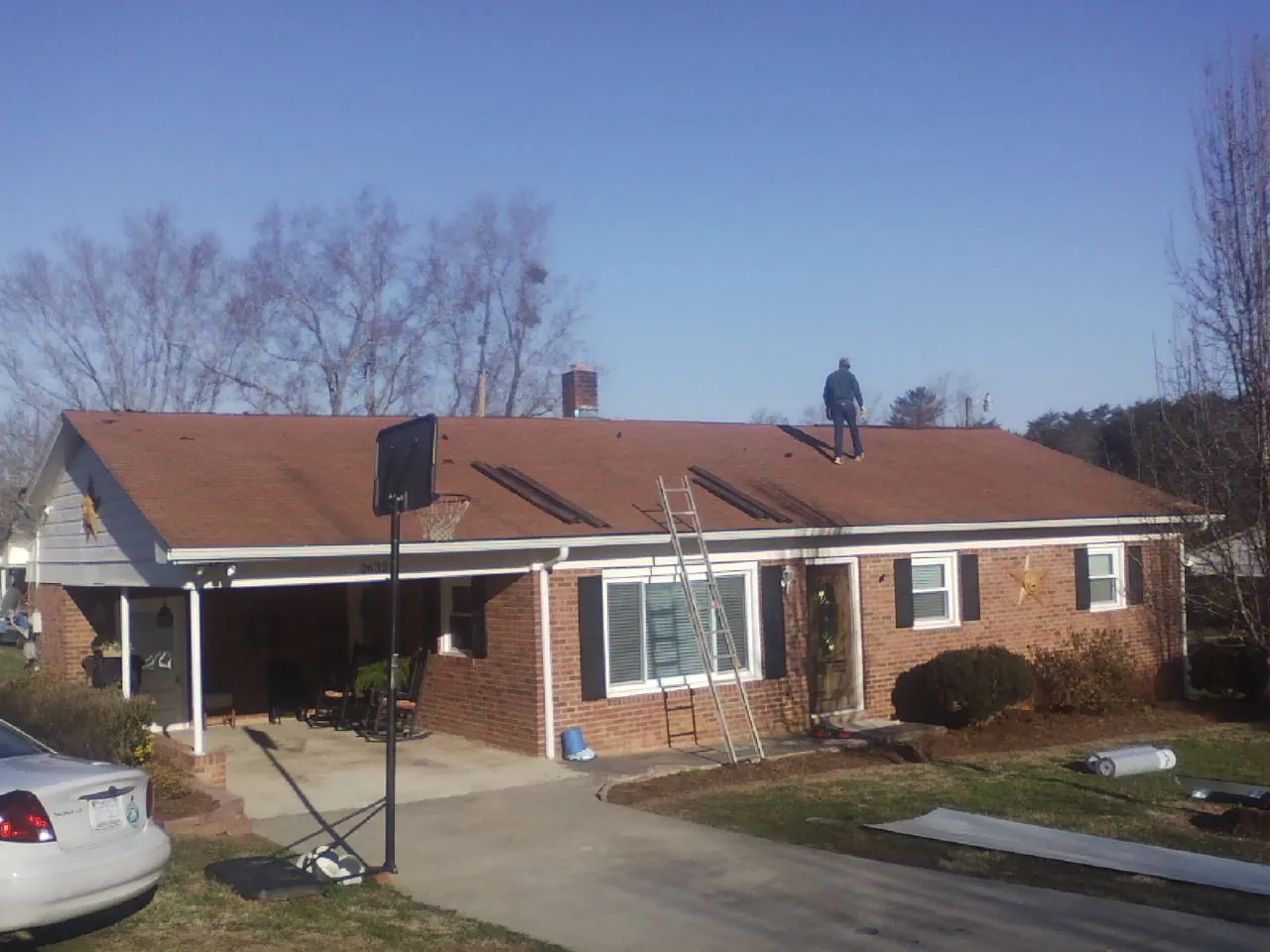 Roofer stripping a shingle roof on a brick ranch before metal panels in Sunnyside