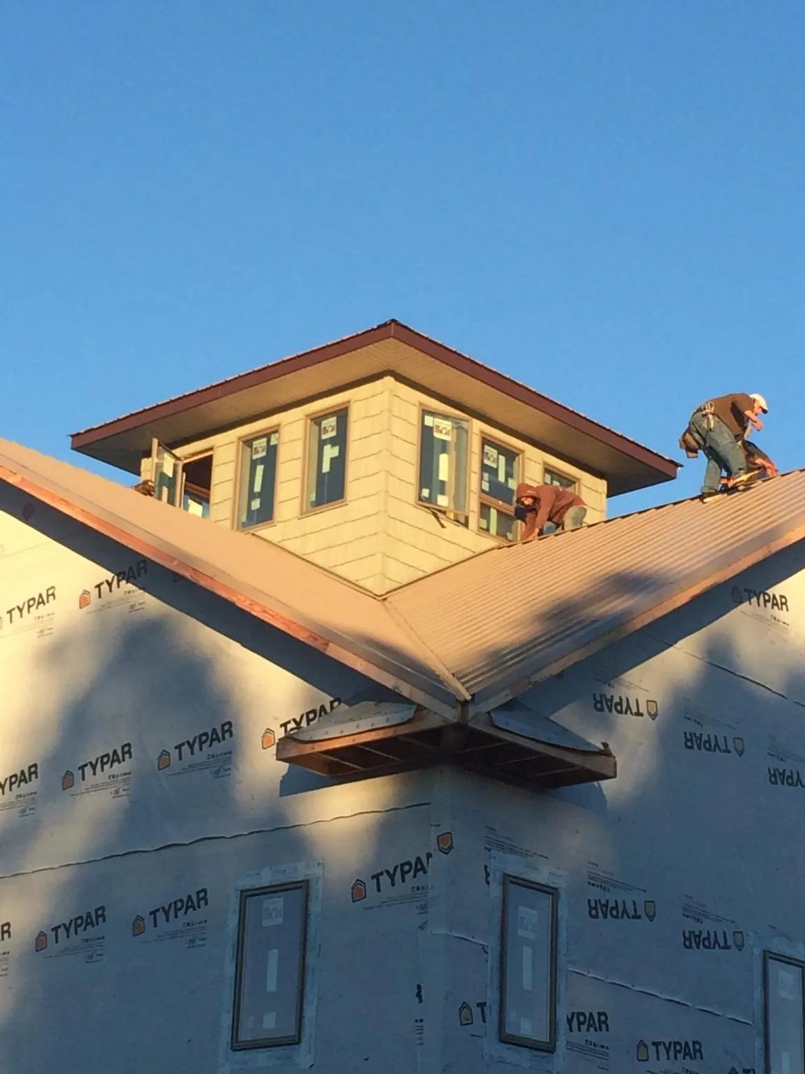 Roofers working around a rooftop cupola on a new metal roof at sunset — Roof Waterproofing in Sunnyside by Roofing Brothers